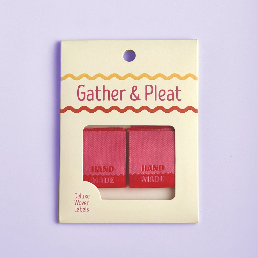 Pack of six 'Hand Made' woven sewing labels in Gather & Pleat retail packaging, on a lilac background.