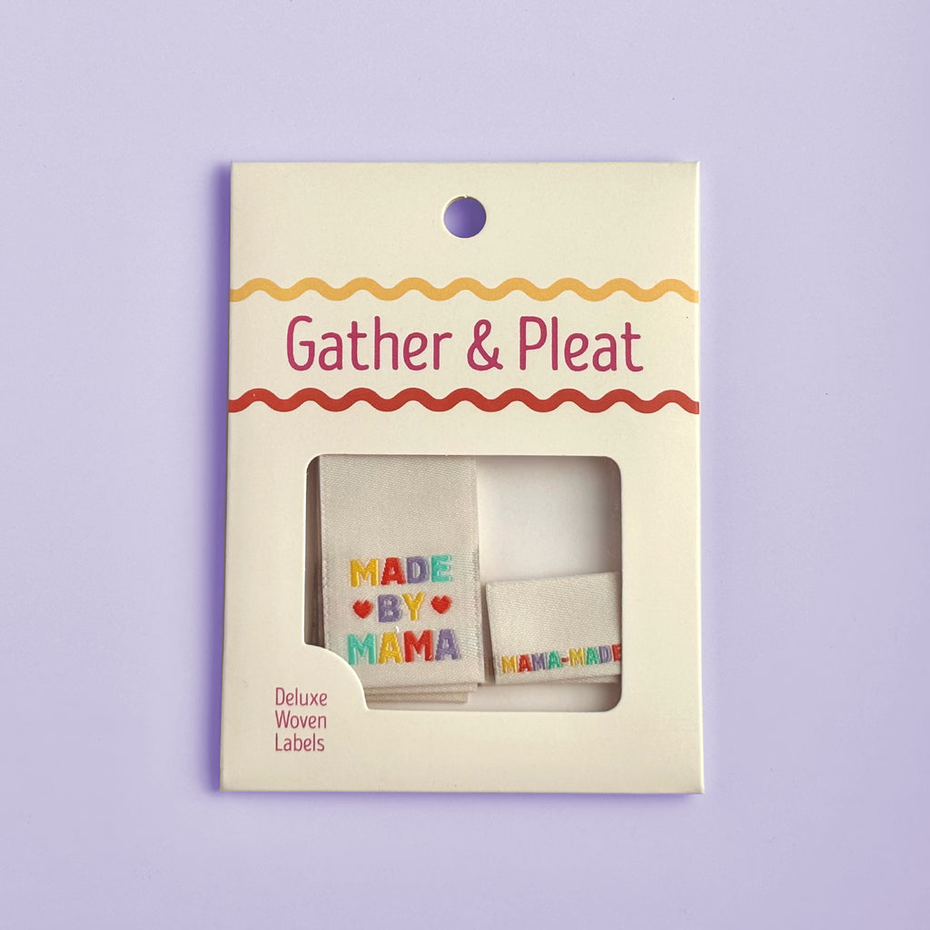Pack of six 'Made by Mama' woven sewing labels in Gather & Pleat retail packaging, on a lilac background.