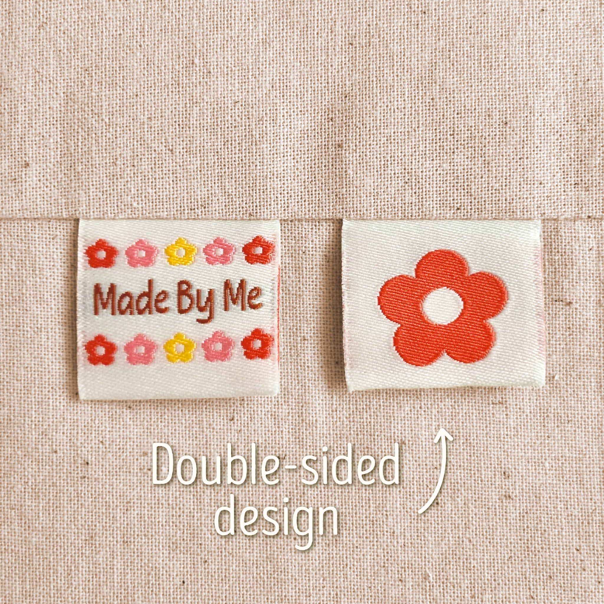 Two small embroidered fabric patches on a beige woven fabric background. The left patch reads “Made By Me” with small multicoloured flowers around it, and the right patch shows a larger red flower. Text in the image explains that this is a double-sided design, implying that the flower is on the back of the 'Made By Me' design.