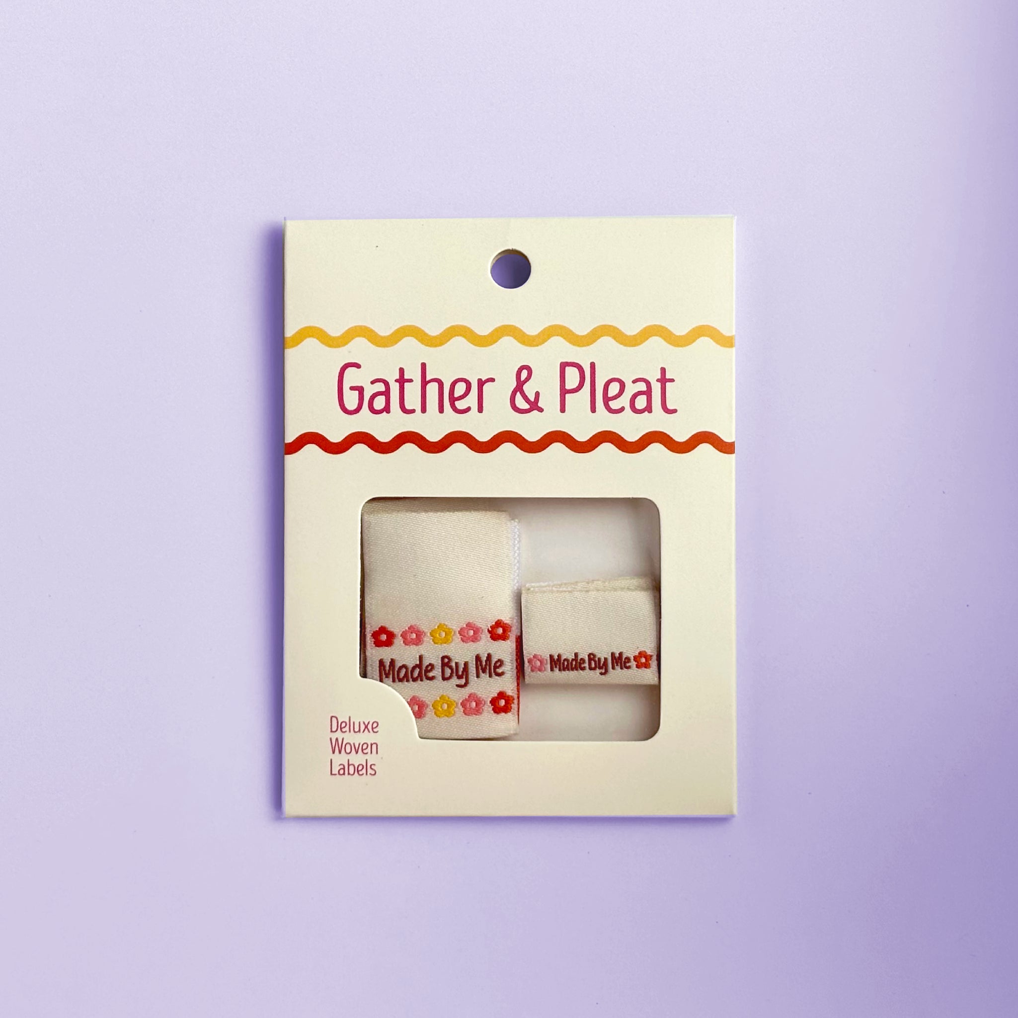 Pack of six 'Made by Me' woven sewing labels in Gather & Pleat retail packaging, on a lilac background.