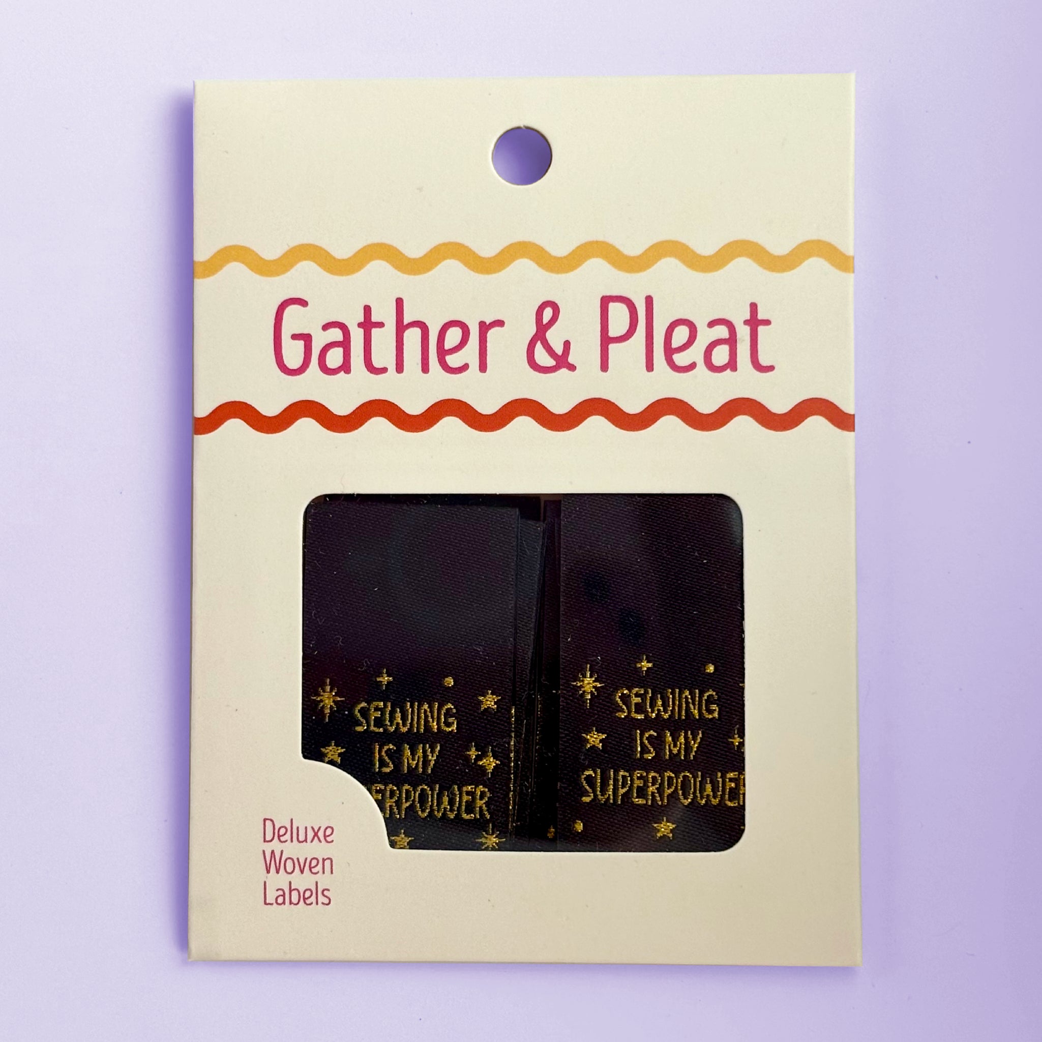 Pack of six 'Sewing Is My Superpower' woven sewing labels in Gather & Pleat retail packaging, on a lilac background.